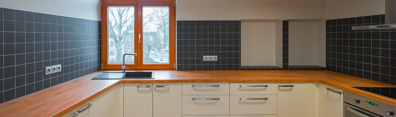 Moderne Küche in Holzoptik mit heller Arbeitsplatte, klaren Linien und eleganter Raumgestaltung nach Küchenumbau in Jülich.