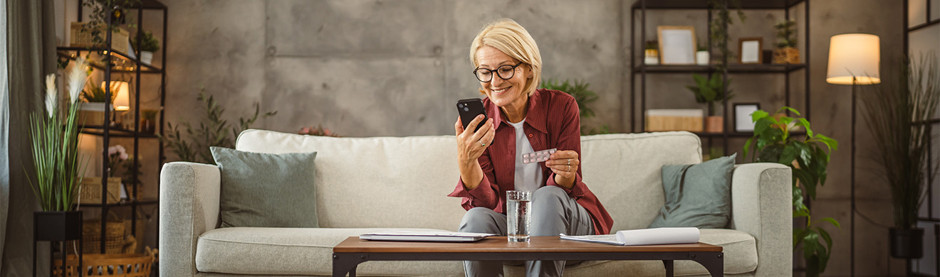 &Auml;ltere Frau pr&uuml;ft Medikamente und liest Gebrauchsanweisungen auf dem Smartphone f&uuml;r sichere Gesundheitsversorgung zu Hause