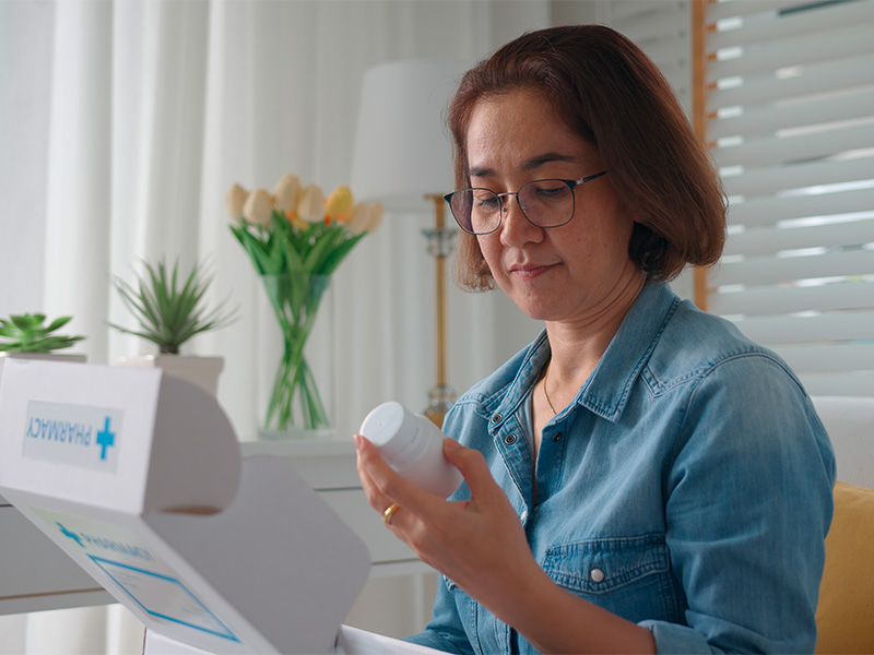 Frau bestellt Gesundheitsprodukte online und erh&auml;lt Medikamentenpaket f&uuml;r moderne medizinische Versorgung zu Hause